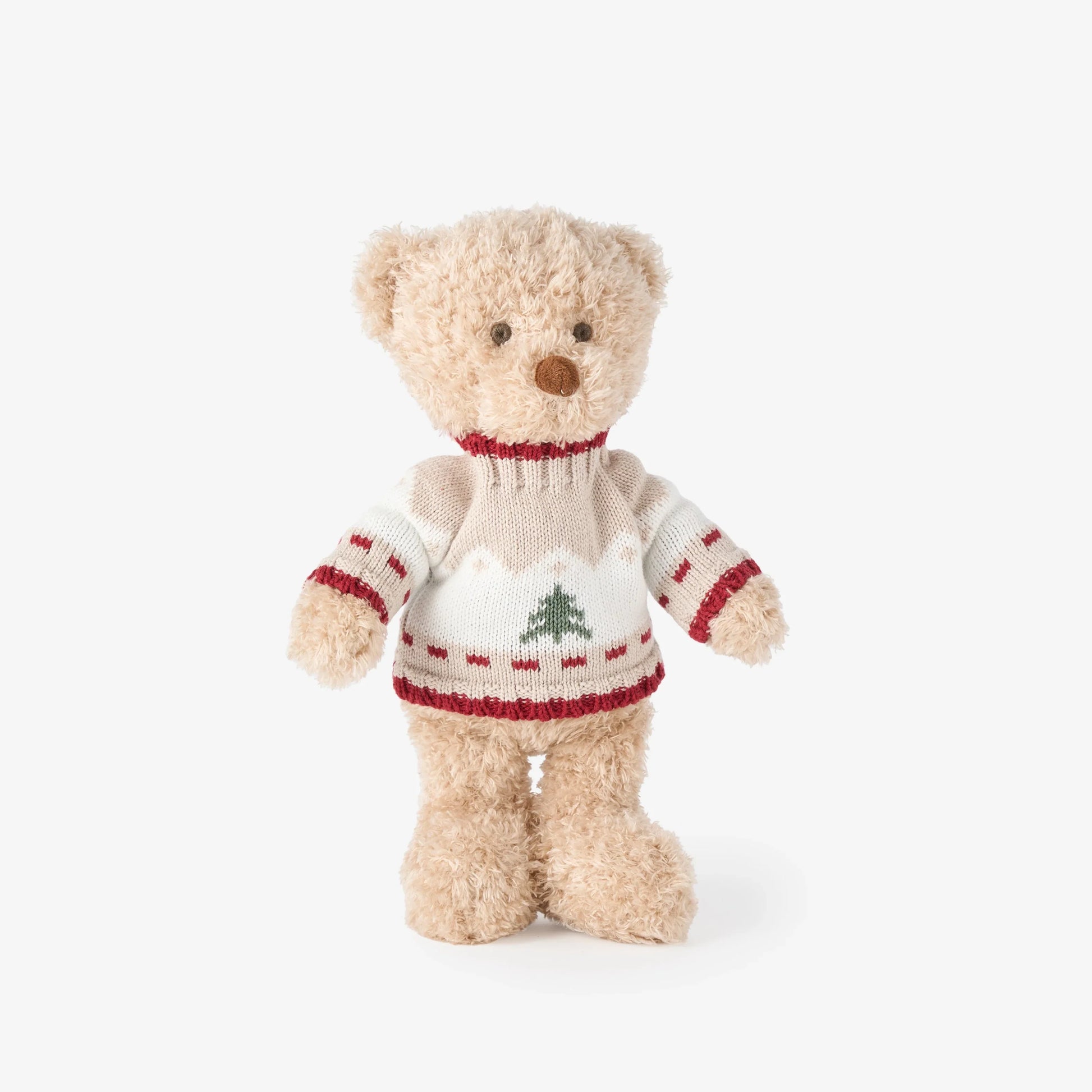 A plush teddy bear wearing a cream knit sweater with red trim and a green Christmas tree motif, photographed against a clean white background.