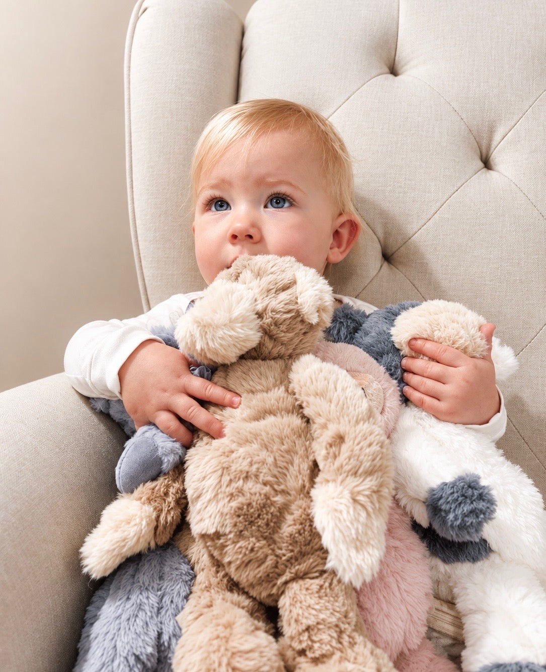 Child seated in a cream chair holding Felix and other plush toys