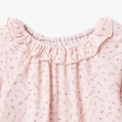 Close-up of blush wildflower baby top with stretchy ruffle collar and floral print on white backgound