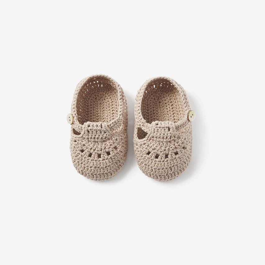 Top view of doeskin beige hand-crocheted T-strap baby booties on white background