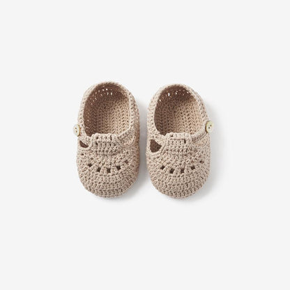 Top view of doeskin beige hand-crocheted T-strap baby booties on white background