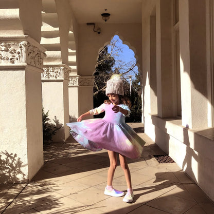 Pastel tie dye girls long sleeve twirl dress worn by child twirling outdoors in pink, blue, lavender, yellow, and mint rainbow colors.