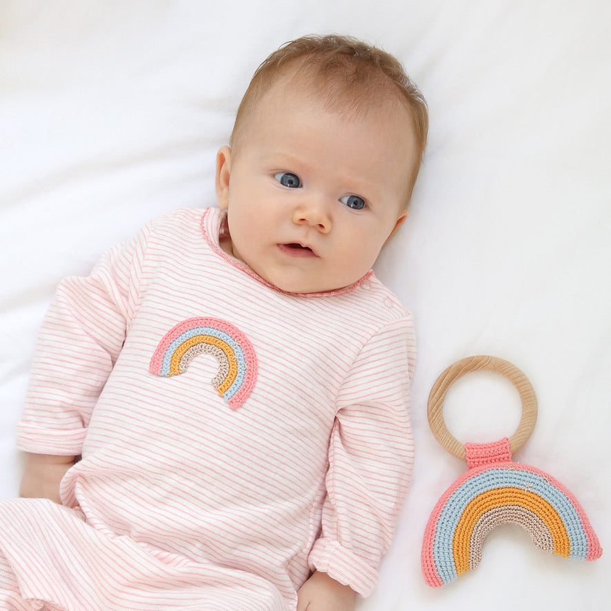 Baby wearing pink striped organic cotton rainbow romper during playtime