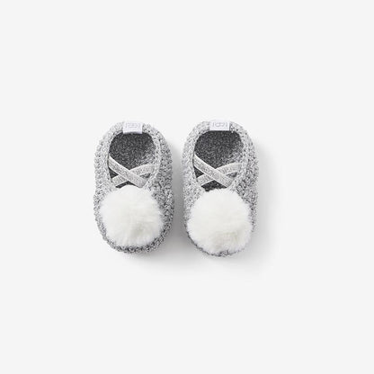 Top view of silver-gray knit baby booties showing the openings and pom-poms on white background